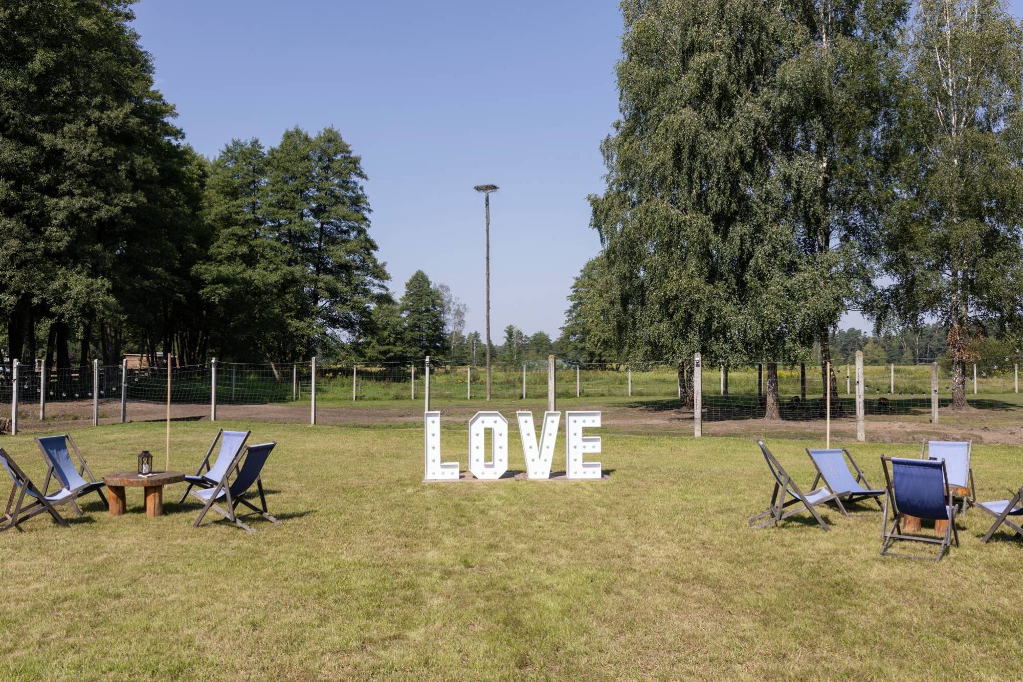 Podświetlany napis LOVE 100 cm w ogrodzie, tło zieleni.